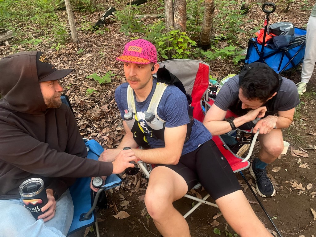 Derek massaging Patrick's left glute at Picnic Area aid station with Mathew looking on gleefully.